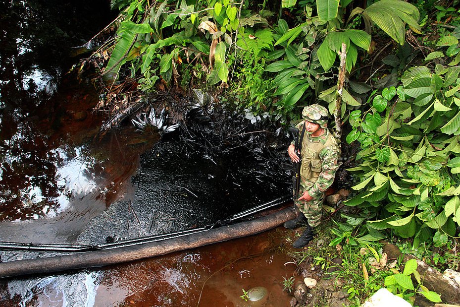 A Colombian solider stands next to a crude oil spill in Puerto Asís, Putumayo. César Mariño García / Pacific Press / LightRocket via Getty Images