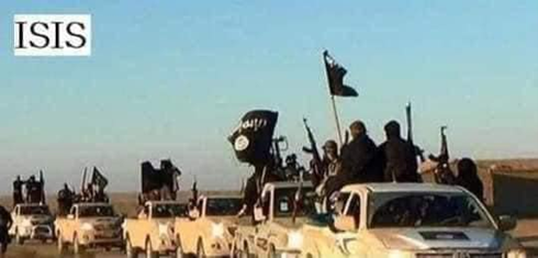 photo of isis fighters dressed in black, waving black flags and guns stood on the back of a convoy of white trucks