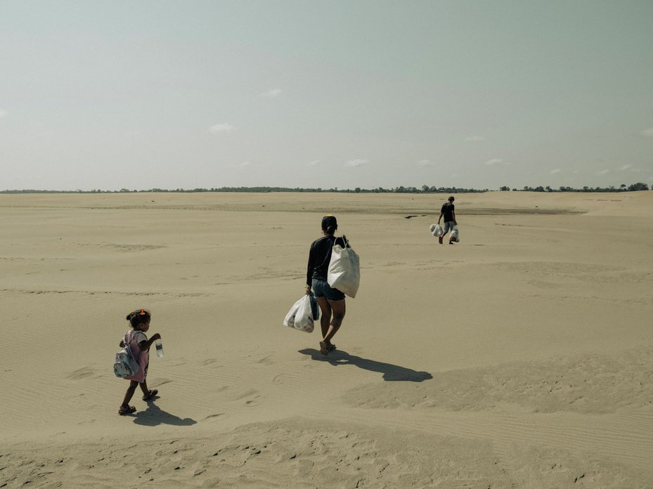 A family walk along a dry riverbed which now separates their community from the Amazon River in Brazil